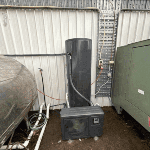 An Ecogenica heat pump hot water system installed outdoors against a metal shed wall.