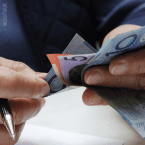 Person counting Australian currency notes representing financial savings and rebates through the VEU program