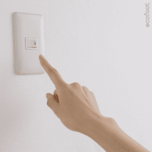 Hand turning on a light switch during home electrification upgrade.