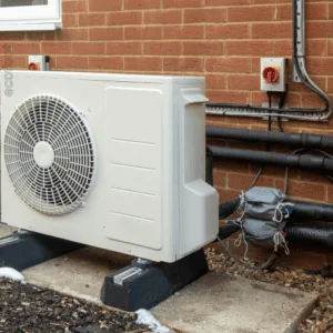 Outdoor heat pump system installed against a brick wall in Victoria.
