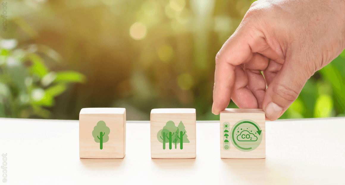 Hand stacking eco-friendly wooden blocks with green energy and environment icons, representing Victoria Energy Upgrades and sustainability goals for 2030.