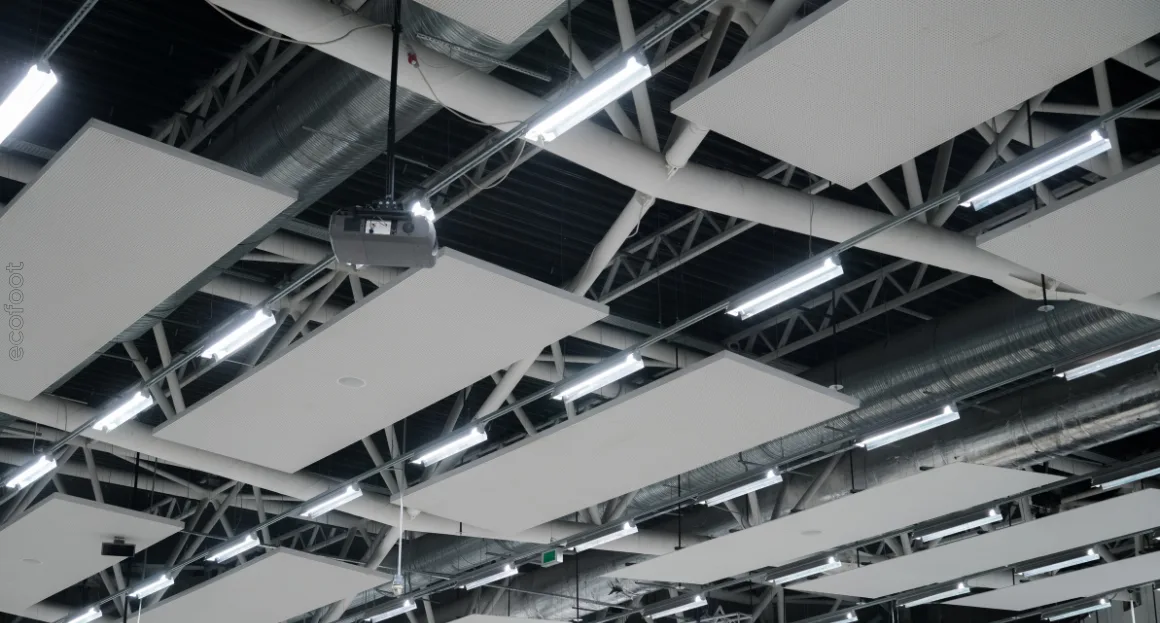 LED lighting installed on an industrial ceiling with metal framework and acoustic panels.