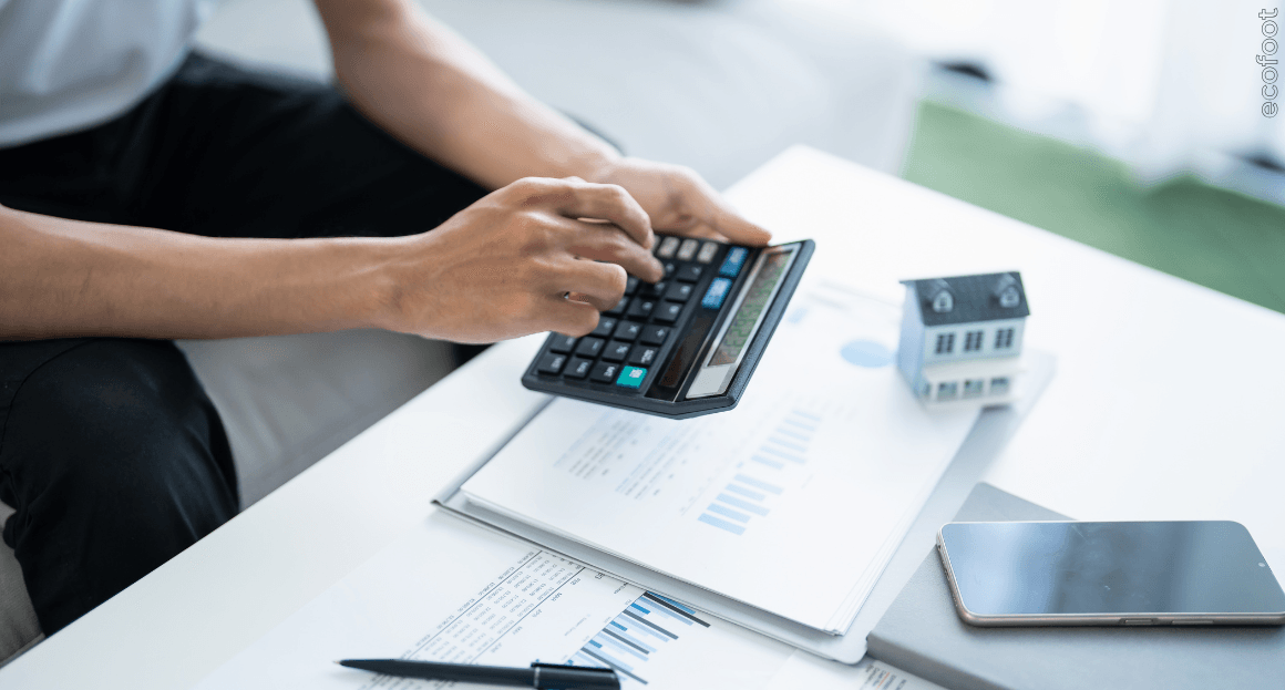 Business owner using a calculator at a desk with financial documents, representing eligibility assessment for the Victorian business solar rebate. 