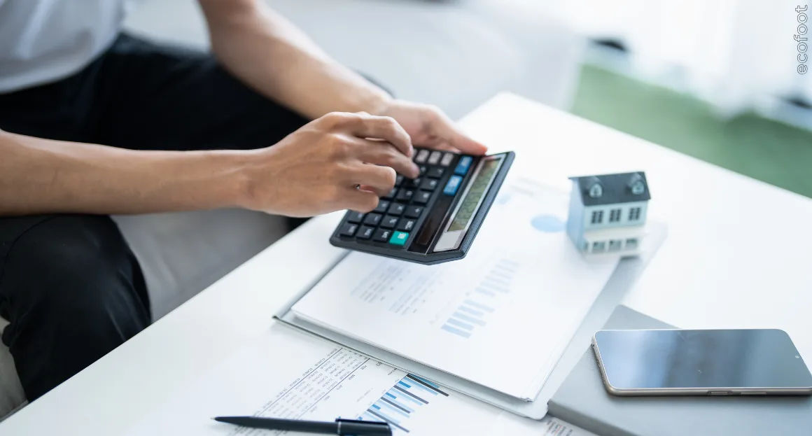 Business owner using a calculator at a desk with financial documents, representing eligibility assessment for the Victorian business solar rebate. 